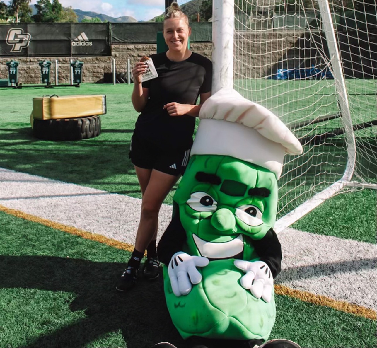 Mac Samuel poses with a pickle mascot during a promotional video shoot for Mr. Pickle's Sandwich Shop