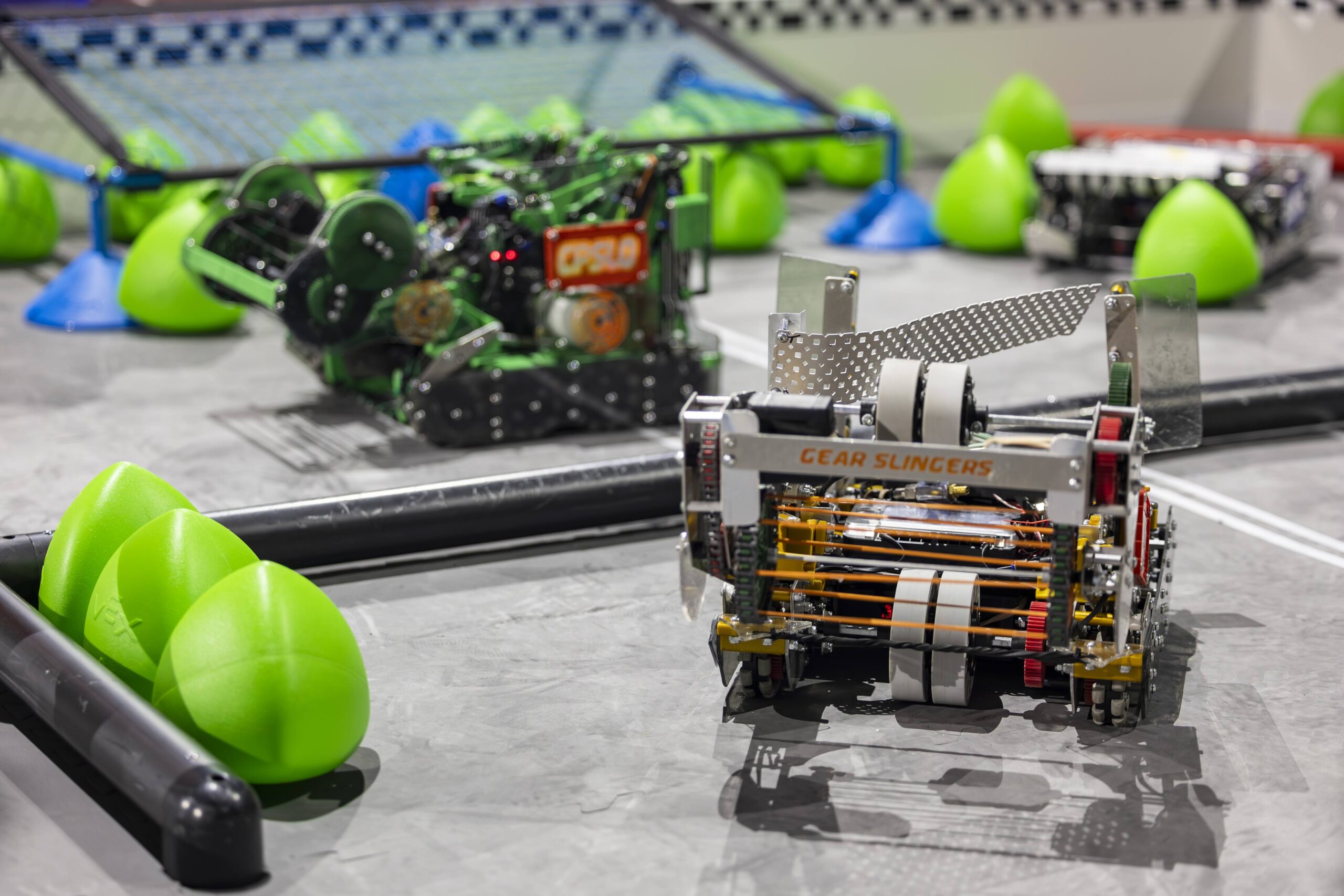 The Gear Slingers' two robots are pictured on the game field with game pieces, Triballs