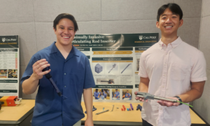 Two students smiling and holding up prototypes of a medical device