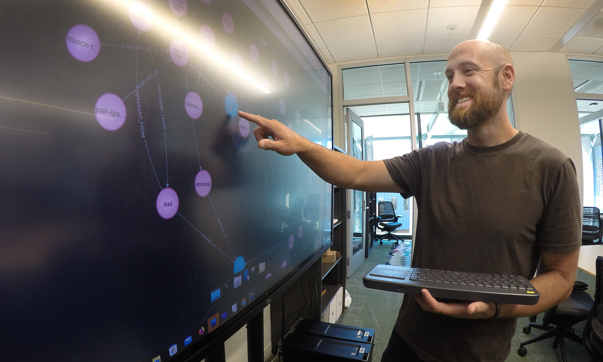 Professor points to digital graphic on the screen in a lab