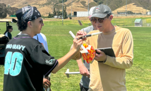 Two students outside with small rockets