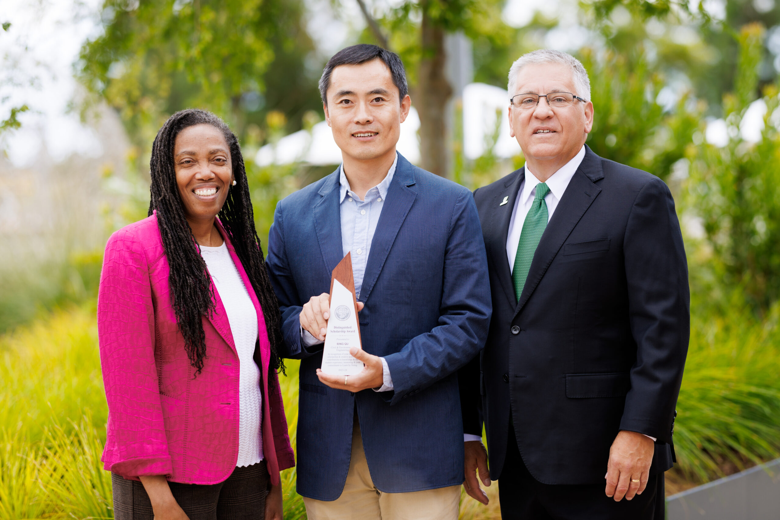 Professor stands with president and provost with his award