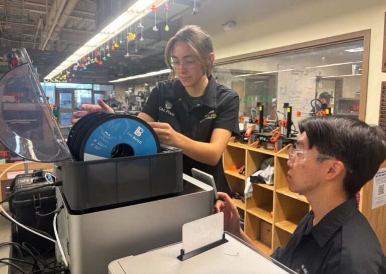 Two shop techs work to repair one of the 3D printers