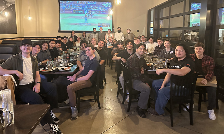 A large group of people at a restaurant smiling for a group photo.