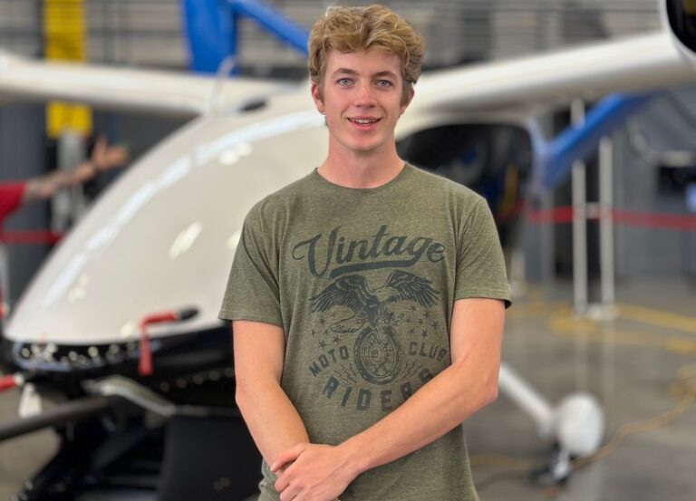 Student stands next to hydrogen-electric demonstrator