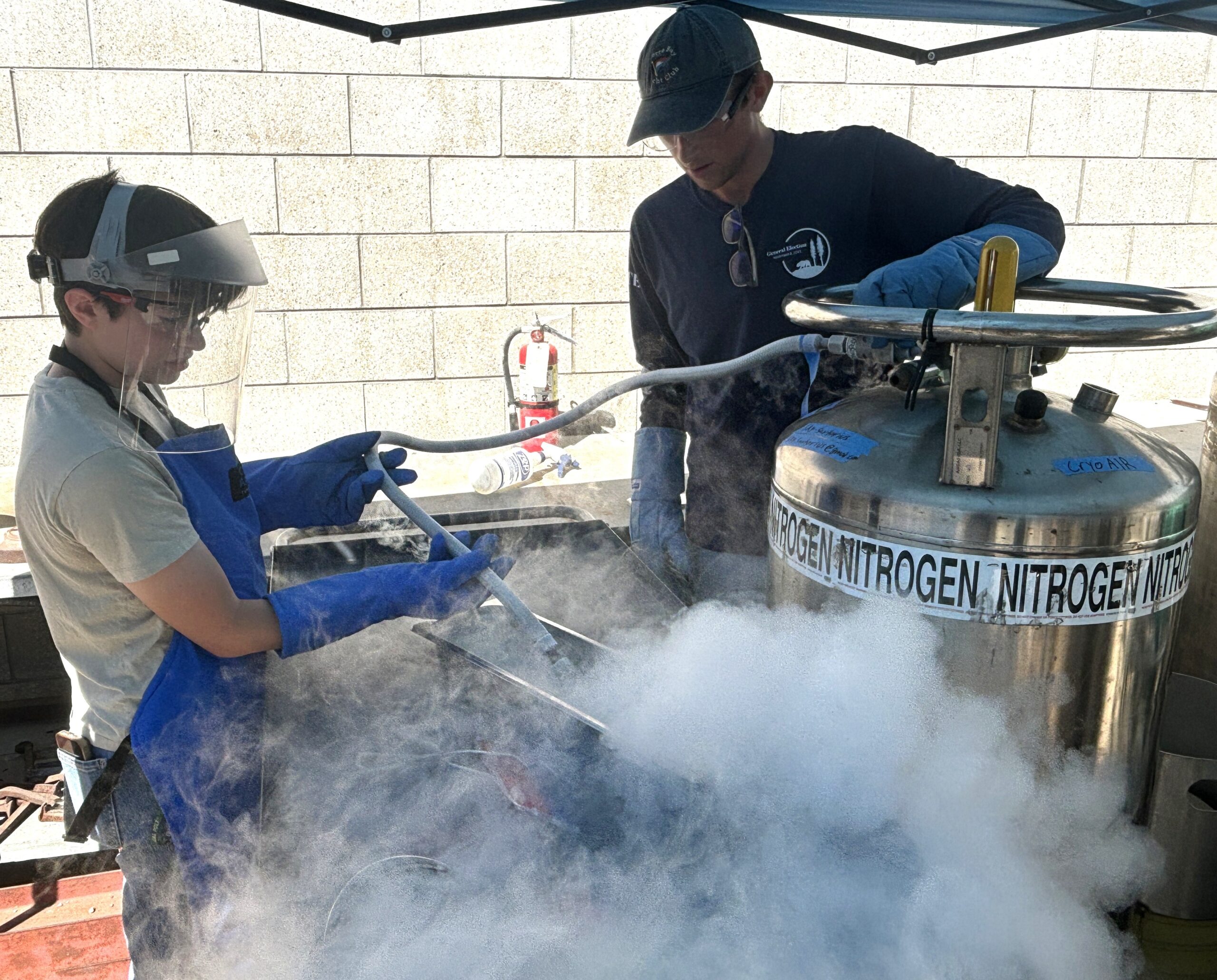 Students fill a pan with liquid nitrogen for an experiment to test safety procedures