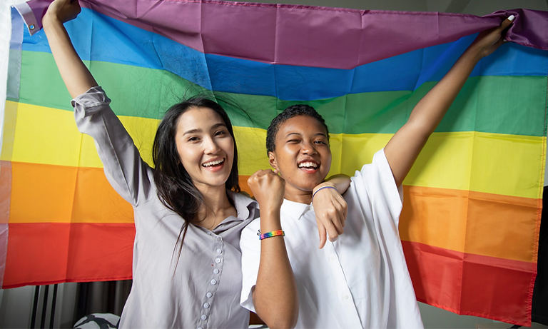 Two people holding up a pride flag.