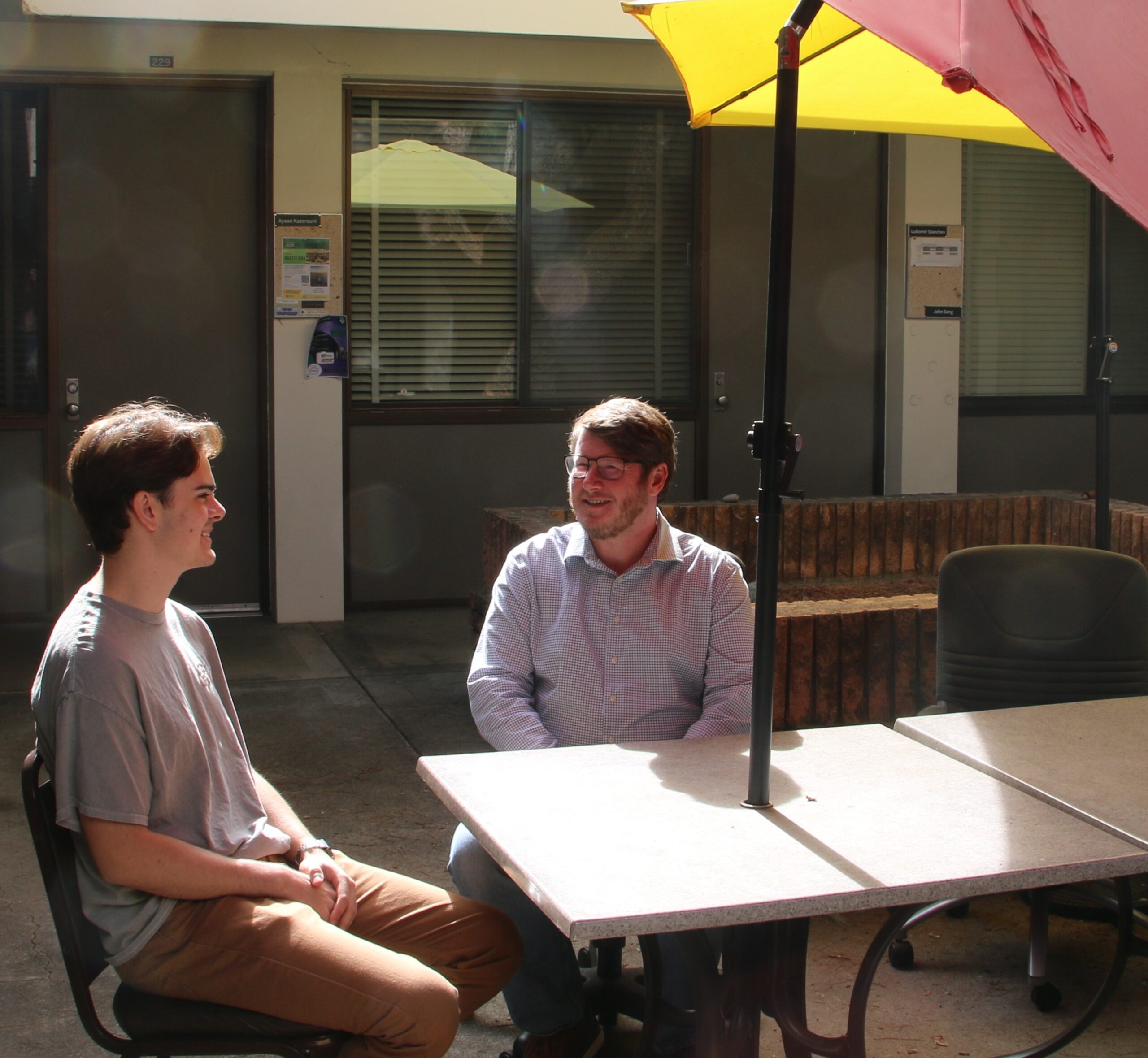 Student and professor sit outside to talk about their project