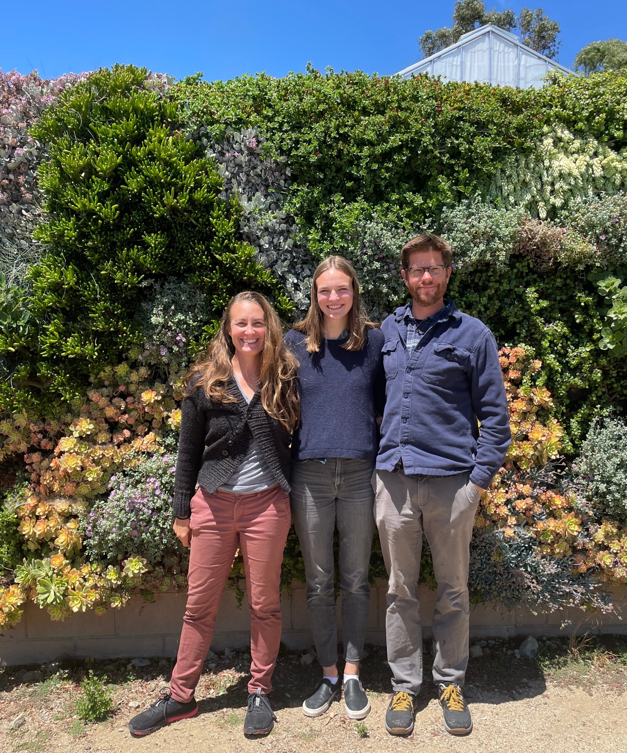 Student with 2 professors stand in Cal Poly's Plant Conservatory