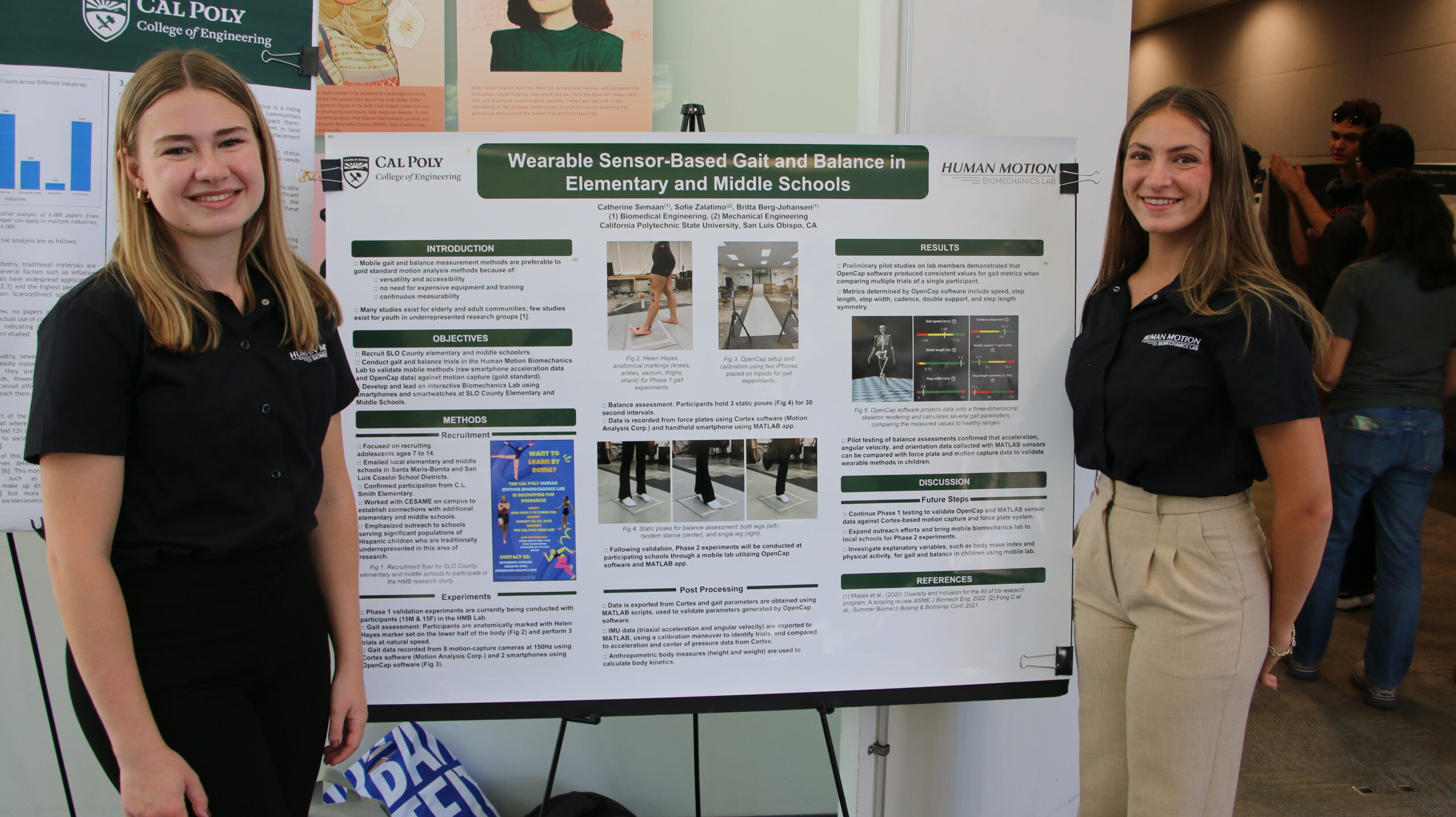 Students stand by research poster during annual symposium