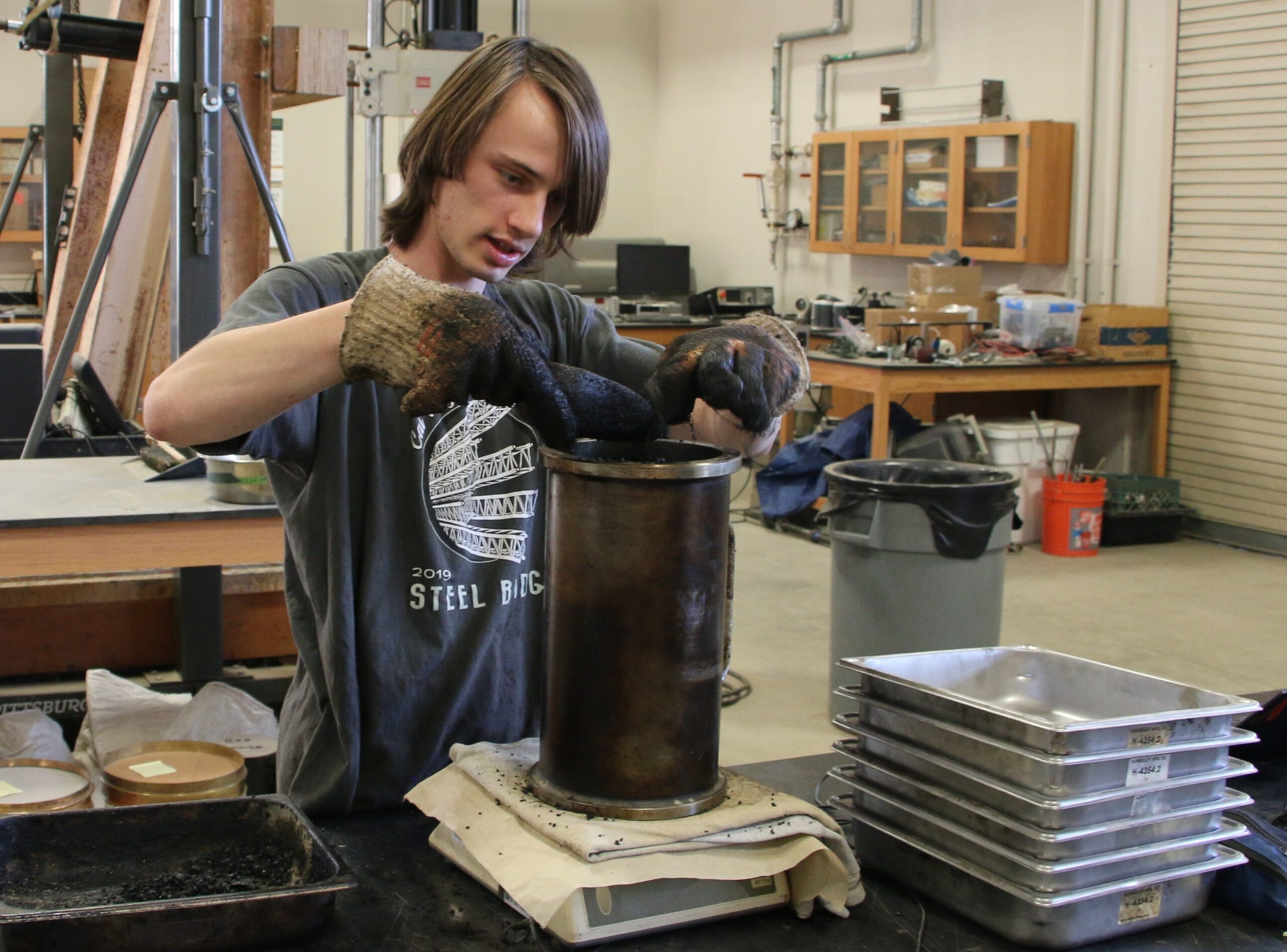 Student works in the Pavement Lab, weighing an asphalt puck