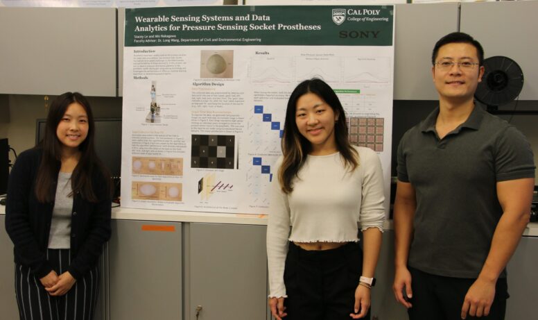 Students and professor stand next to project poster