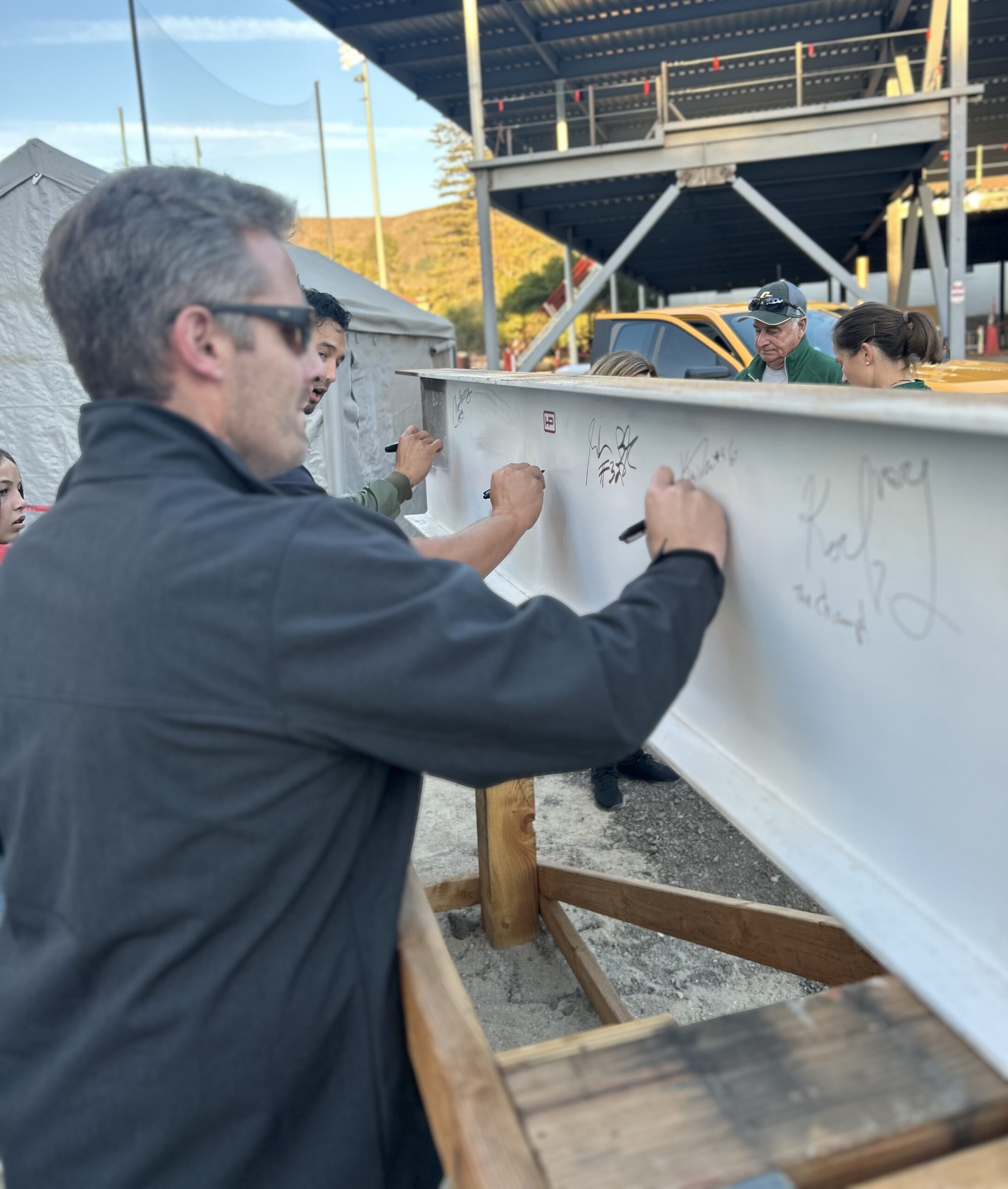 Kelly Turbin signs a beam that will be part of the John Madden Football Center