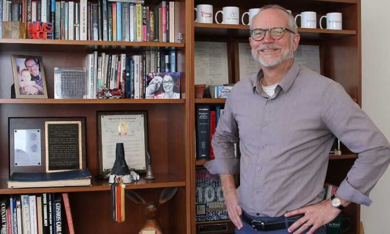 Interim Dean Robert Crockett standing in front of the bookshelf in the dean's office.