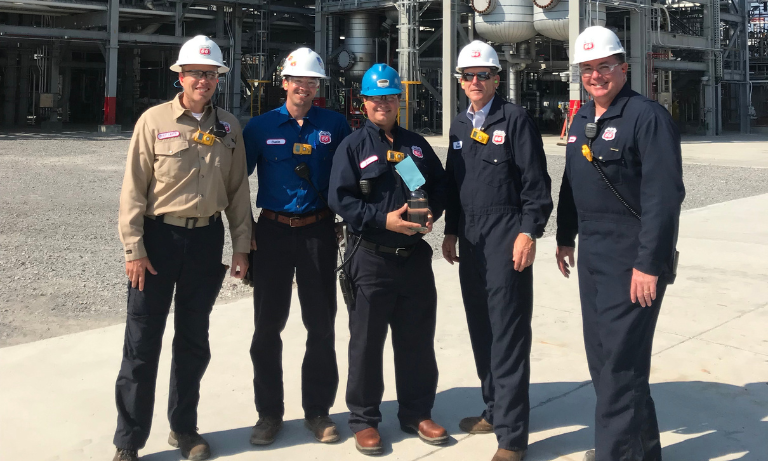 Five men with hard hats smiling at the camera.