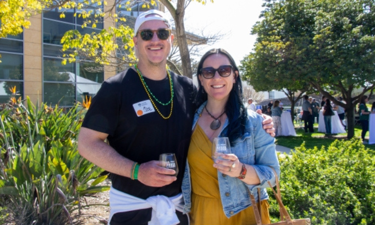 Two people holding wine glasses at the Cal Poly Alumni Wine and Beer Garden event.