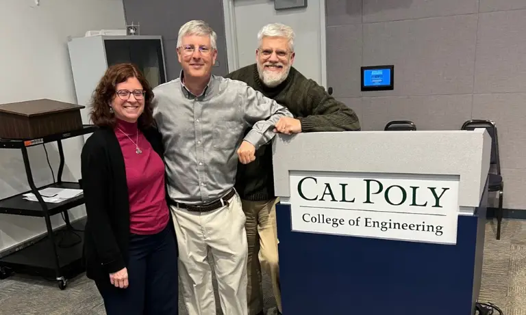 Three people standing next to a podium