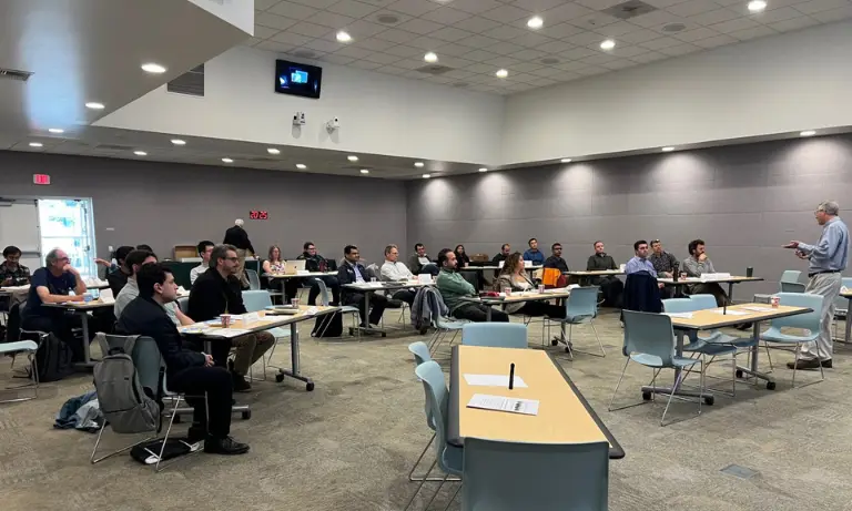 A group of people in a room listening to a speaker.