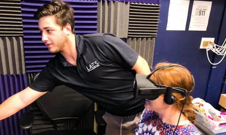 A woman with a VR headset on and a man in the room with her