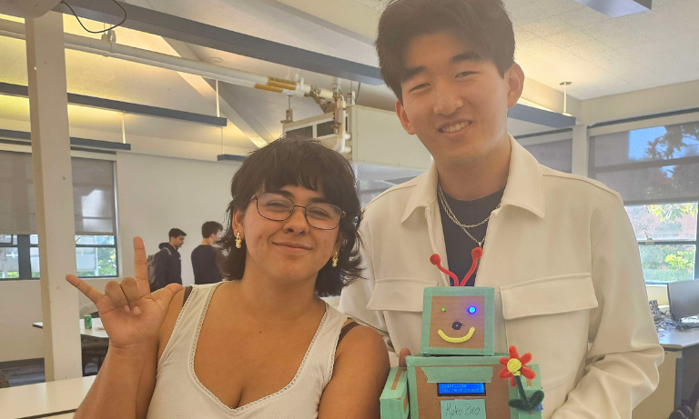 Two students holding a small robot that they built.
