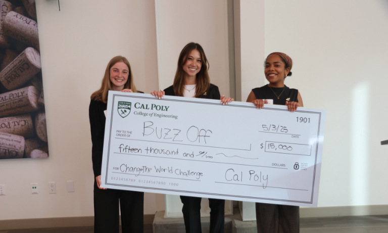 Three students holding a giant check.
