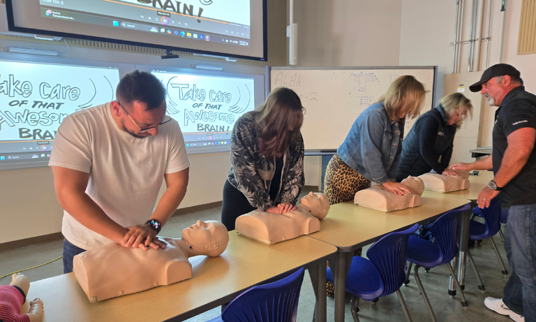 Four people practicing CPR on dummies