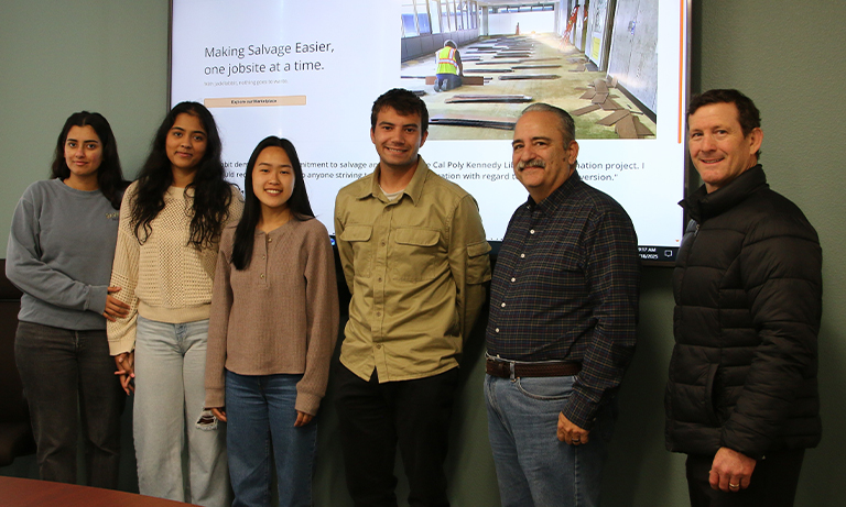 Project group gathers in front of screen project website image