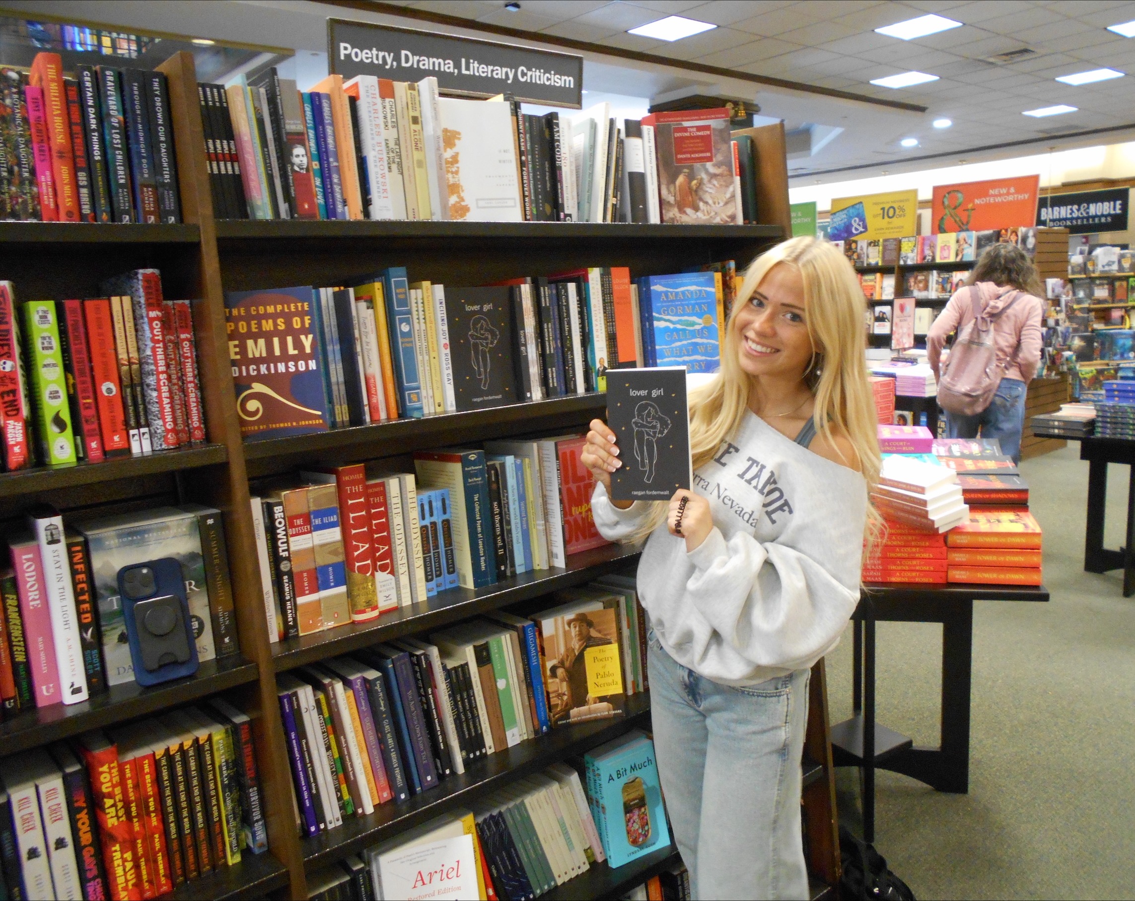 Student holds up poetry book at local bookstore