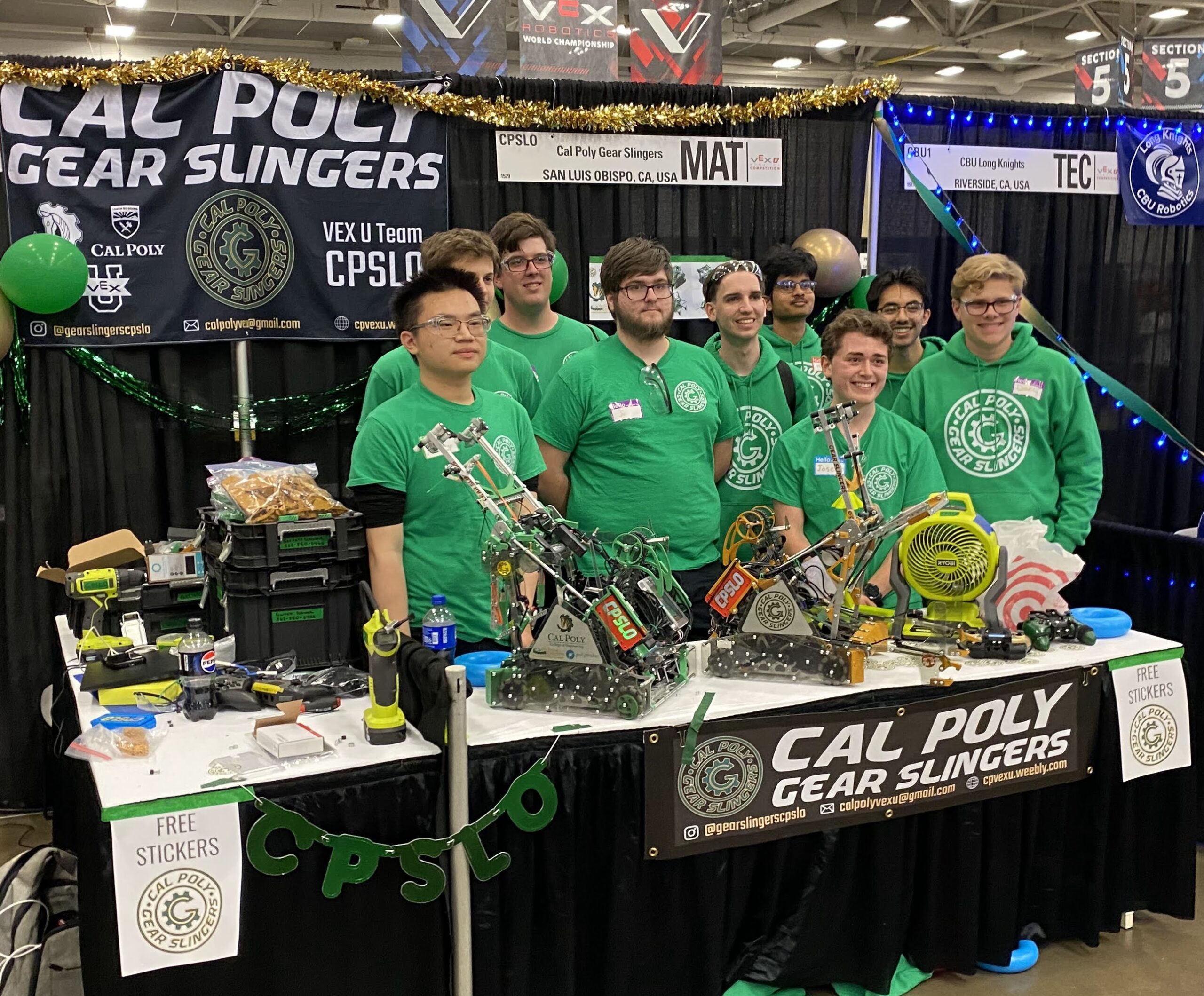 Team poses next to their pit station with robots, swag and gear