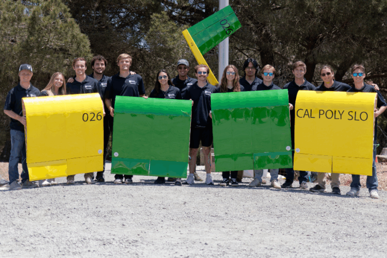 Students in a row posing and holding up airplane parts.