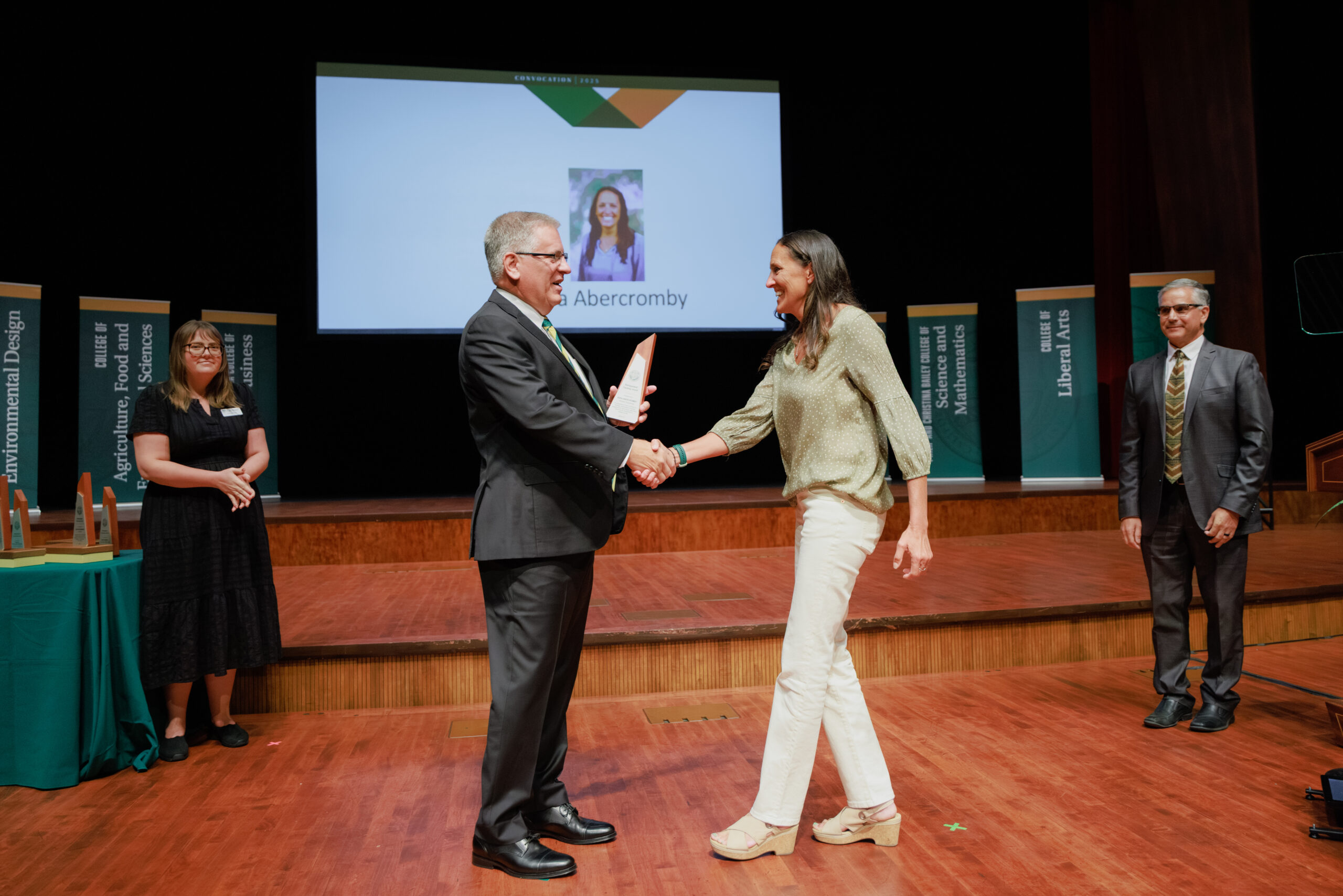 Professor shakes hand of university president onstage