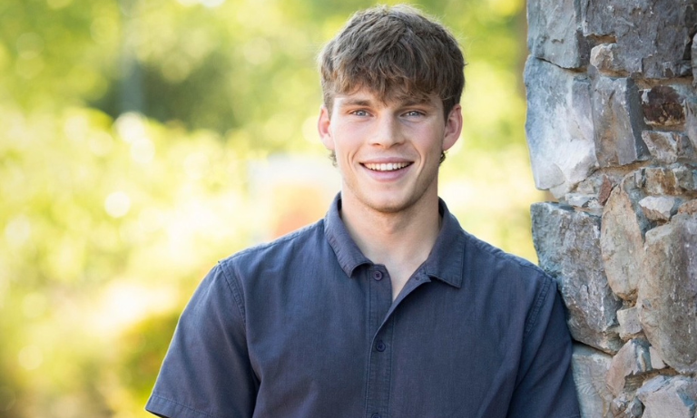 Headshot of a Cal Poly student leaning against a tree with foliage in the background