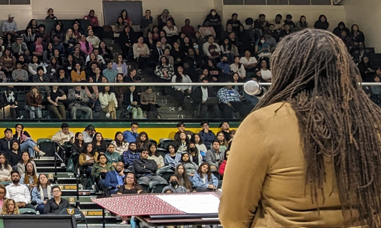 A woman standing at a podium speaking to a crowd of students