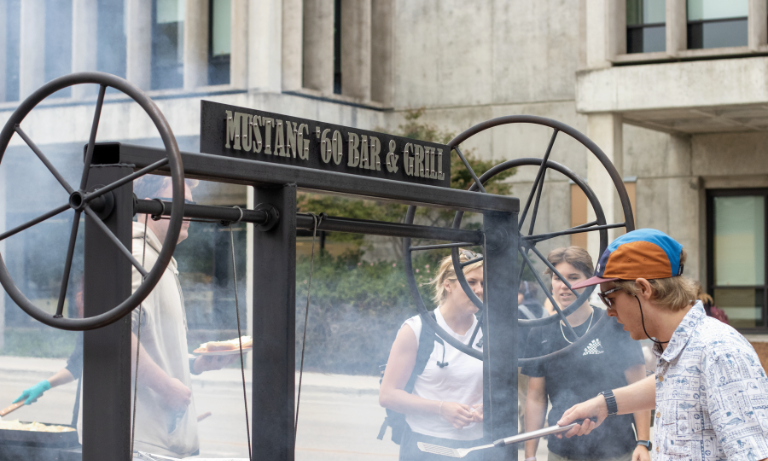 A student cooking on a barbecue pit