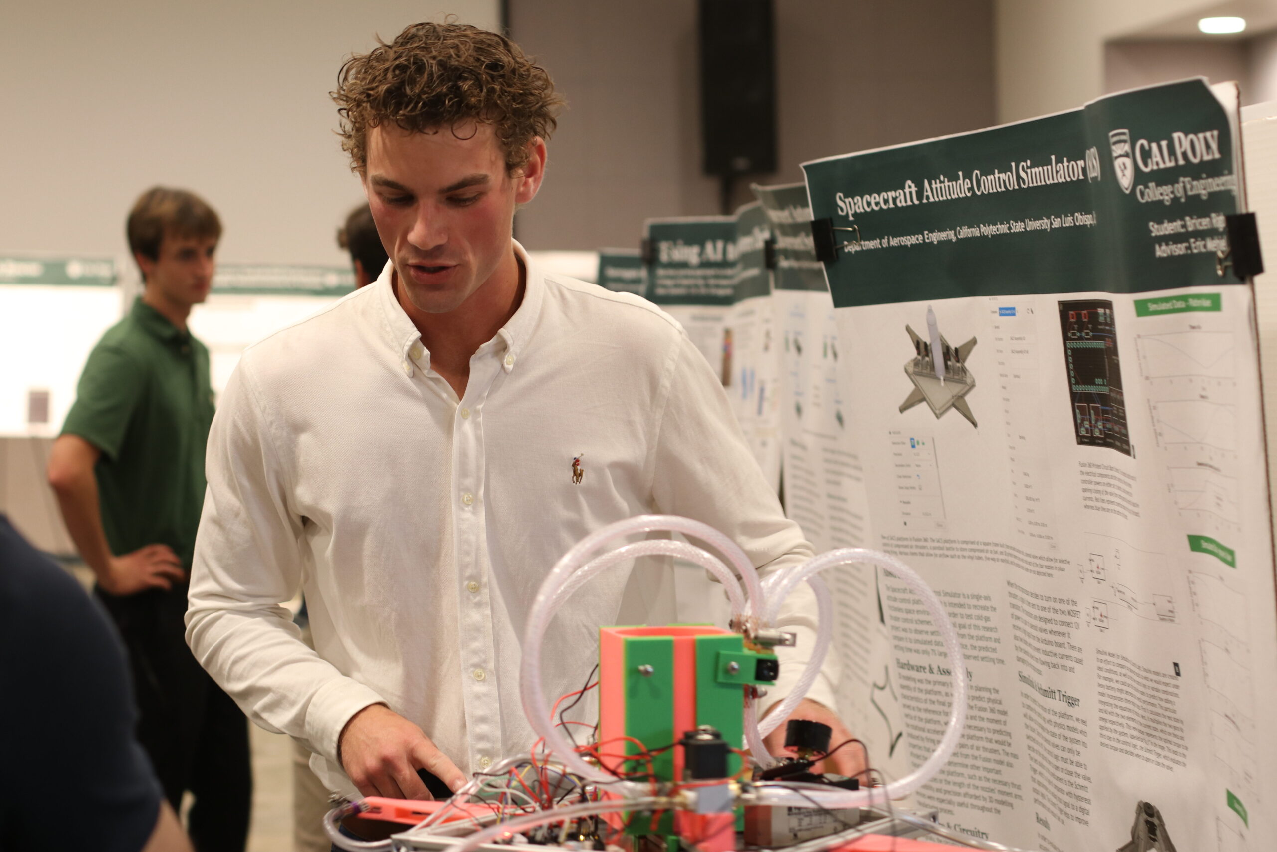 A student detailing his Summer Undergraduate Research Program project to onlookers