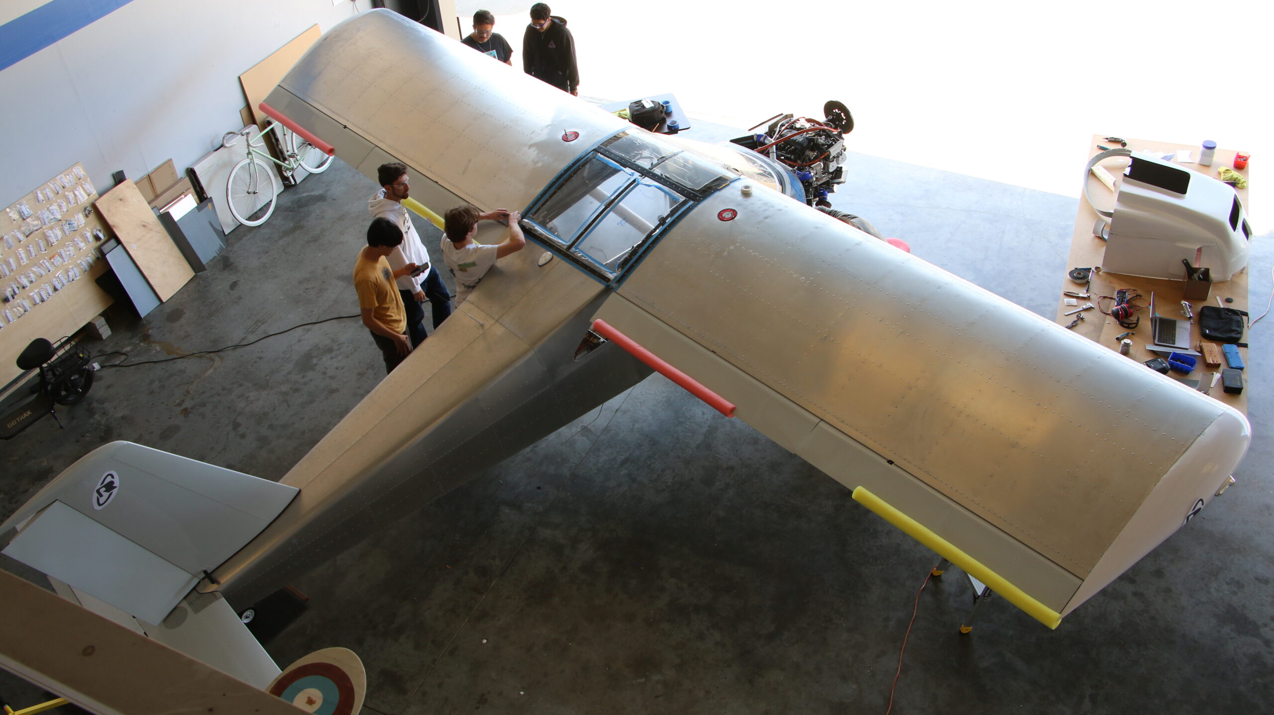 Students gather around the airplane in the hangar