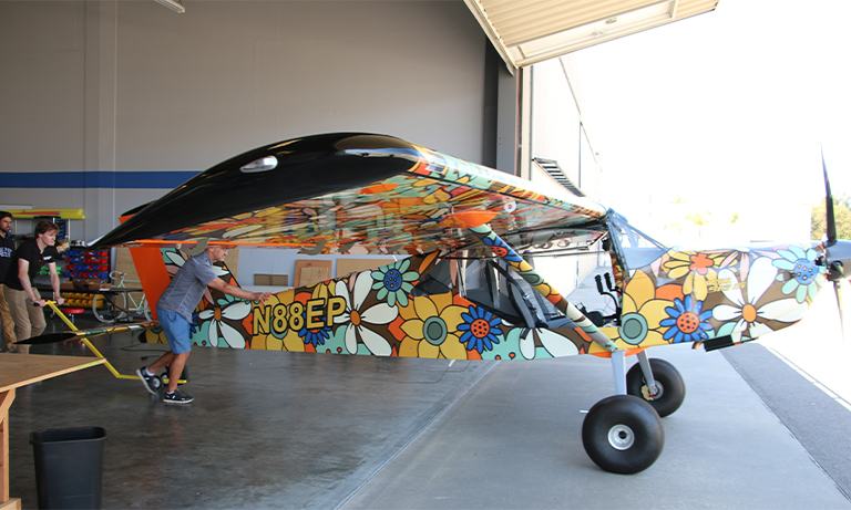 Professor and student wheel airplane out of hangar