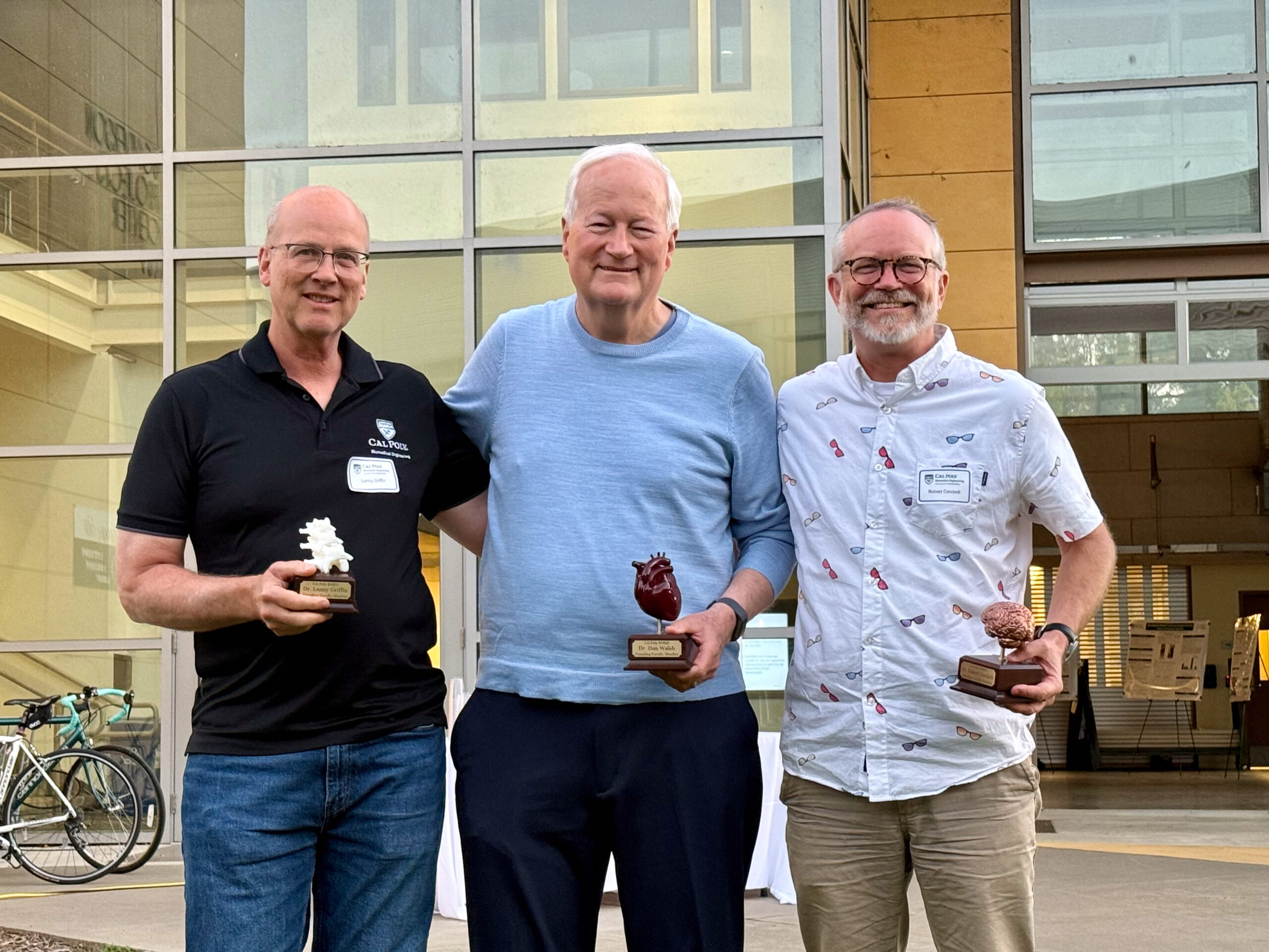 Photo of three men holding awards