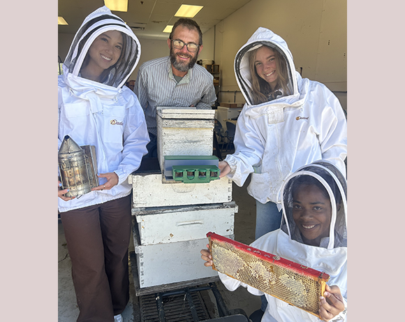 Students pose with hive, prototype and other beekeeper materials