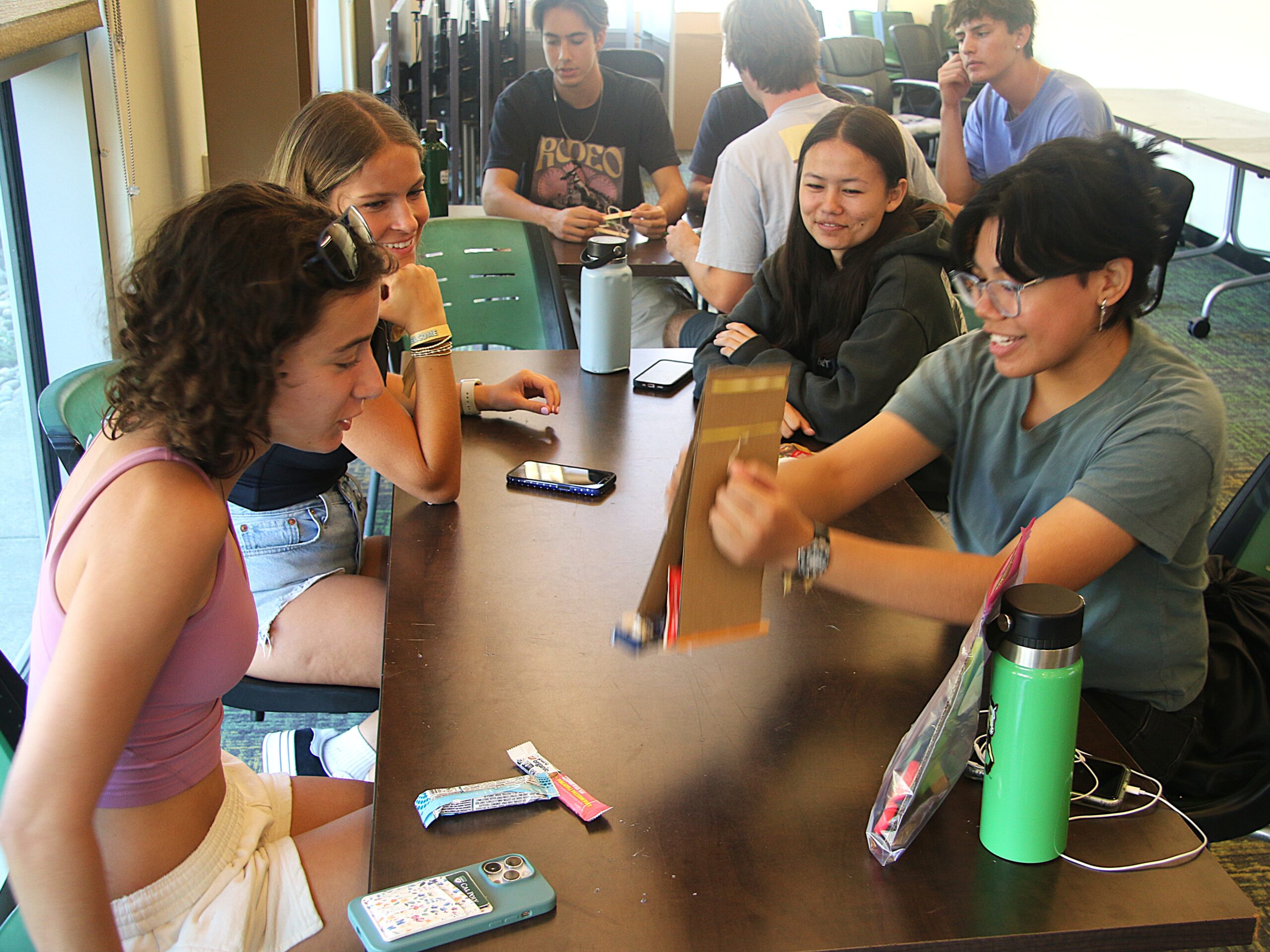 Students pick up snacks with the "robotic arm" they constructed from cardboard