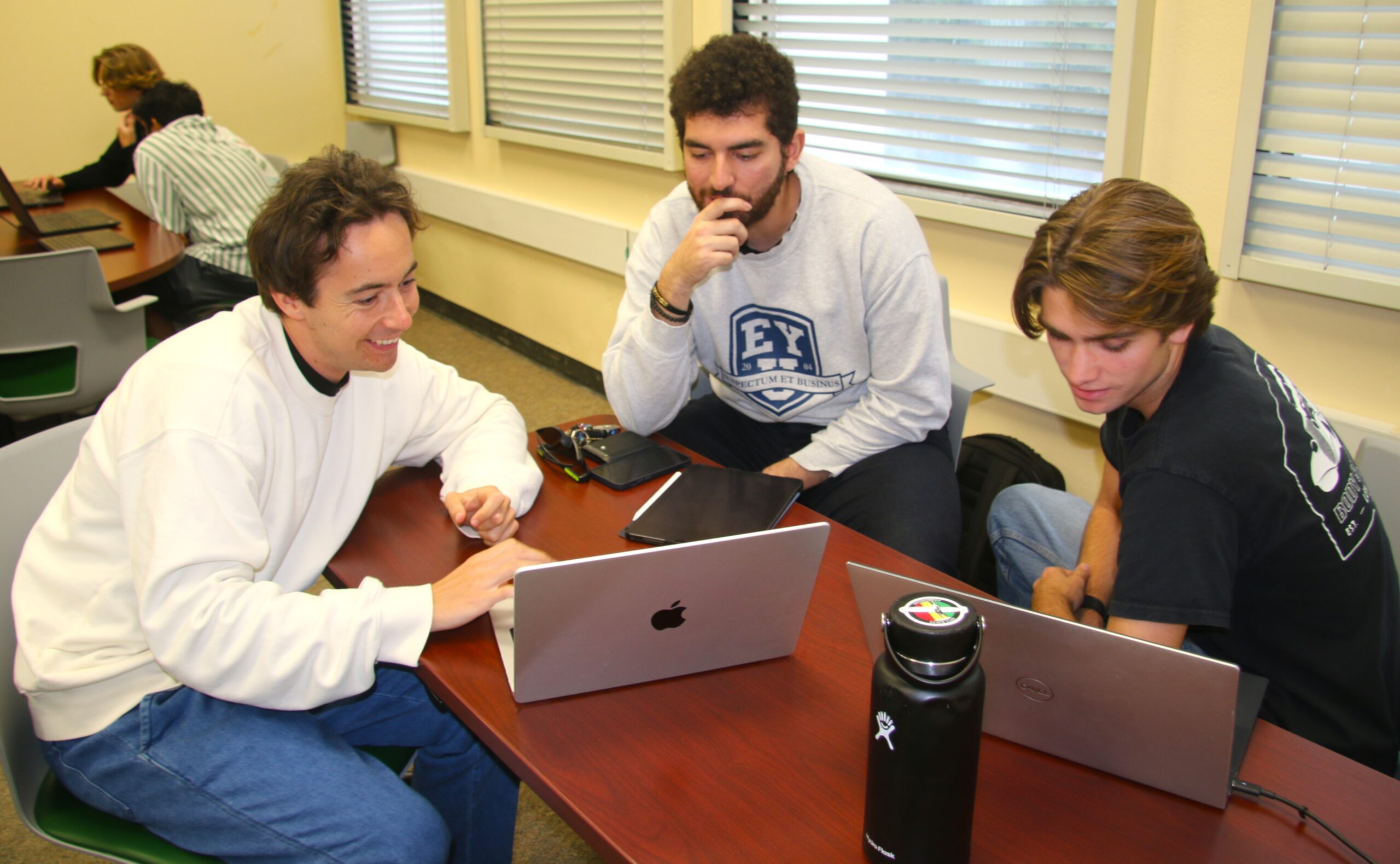 Researcher works with students over laptops in lab