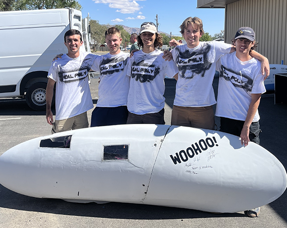 Students stand next to human-powered vehicle