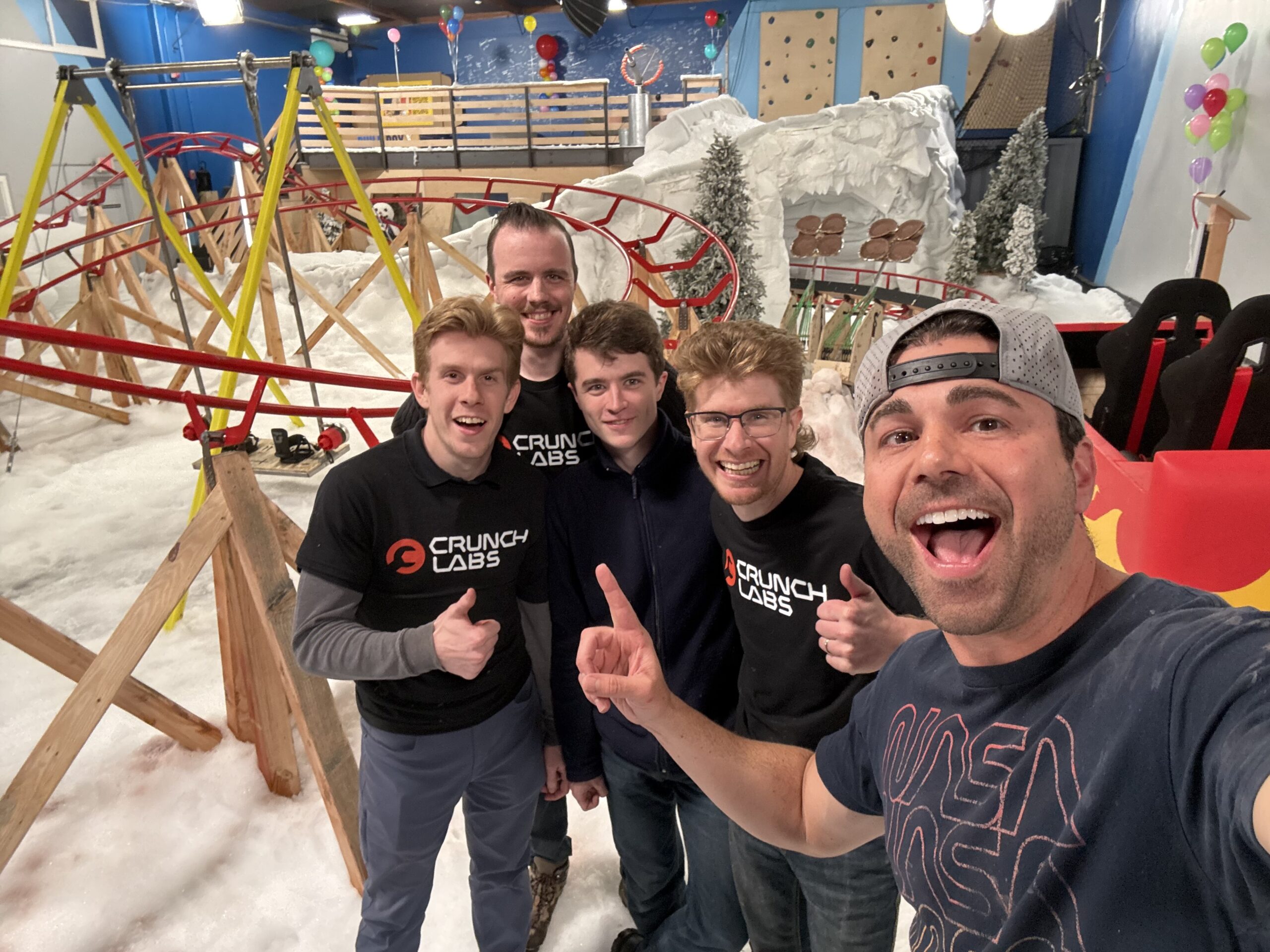Five people standing in front of an indoor roller coaster