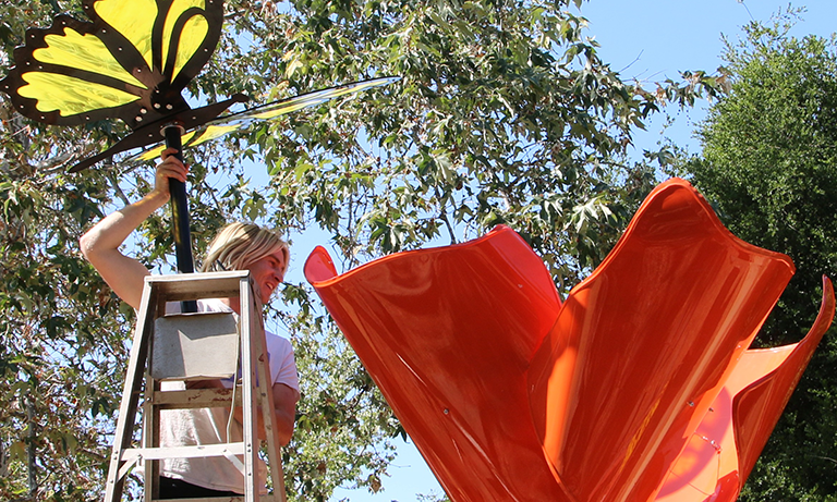 Student putting butterfly sculpture piece into poppy