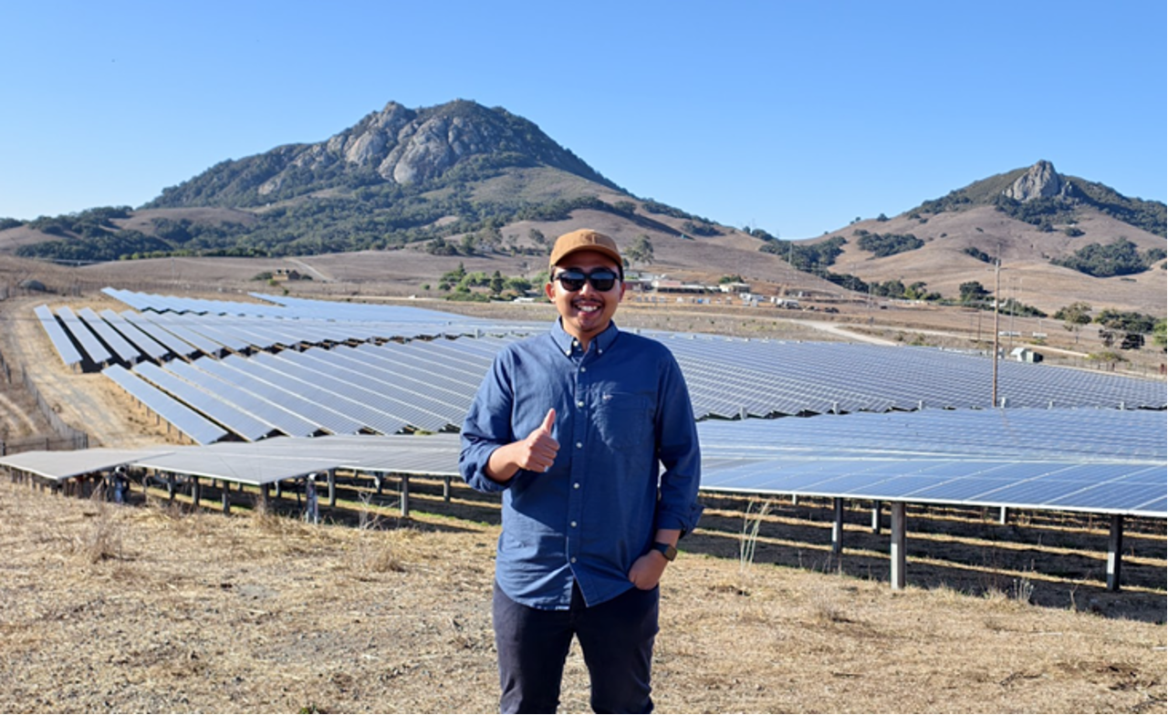 Visiting professor stands near solar panels at Cal Poly's solar farm