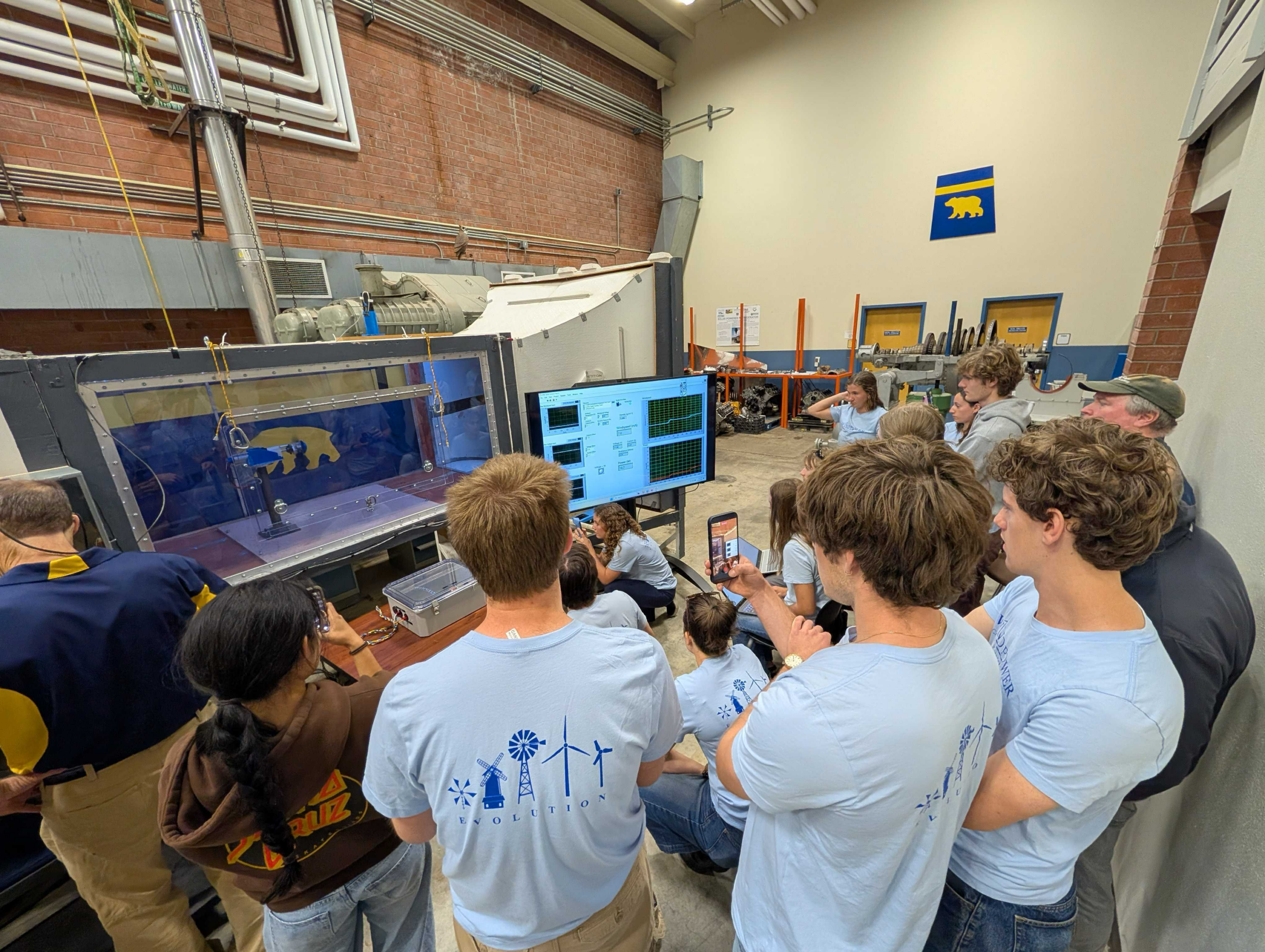 Students watch their turbine as it undergoes testing in the wind tunnel